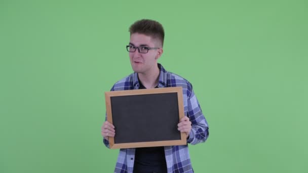 Fröhlicher junger Hipster-Mann spricht, während er eine Tafel hält — Stockvideo