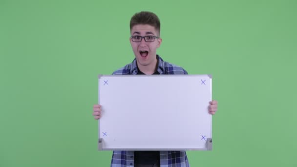 Feliz joven hipster hombre sosteniendo la pizarra blanca y mirando emocionado — Vídeos de Stock