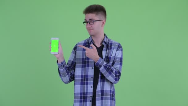 Feliz joven hipster hombre mostrando el teléfono y dando pulgares hacia arriba — Vídeos de Stock