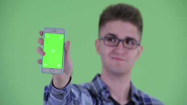 Лицо счастливого молодого хипстера, показывающего телефон — стоковое видео