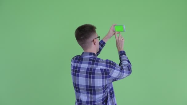 Rückansicht eines jungen Hipster-Mannes, der mit dem Handy fotografiert — Stockvideo