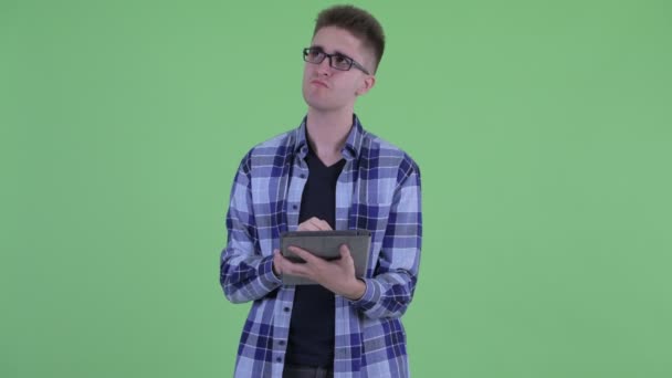 Lycklig ung hipster man tänkande när du använder digital Tablet — Stockvideo