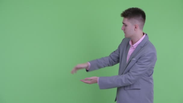 Šťastný mladý obchodník chytne prsty a něco ukazuje — Stock video