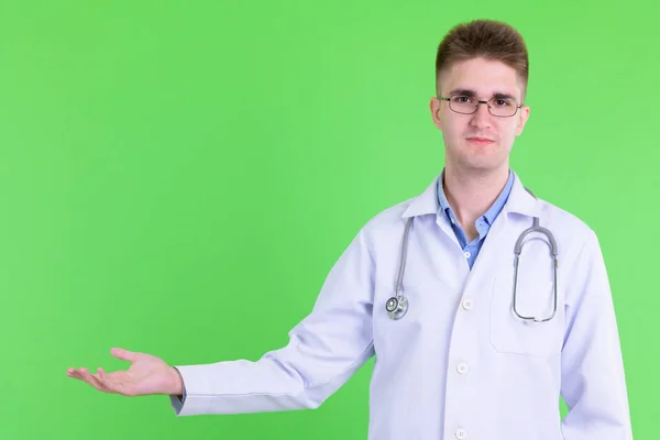 Portrait of young handsome man doctor showing something — Stock Photo, Image
