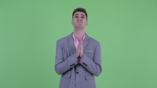 Young businessman praying and looking up — Stock Video