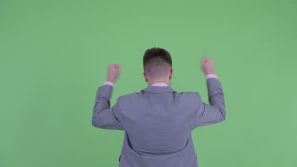 Вид ззаду щасливого молодого бізнесмена з піднятими кулаками — стокове відео