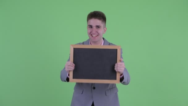 Šťastný mladý obchodník držící tabuli a vypadal překvapeně — Stock video