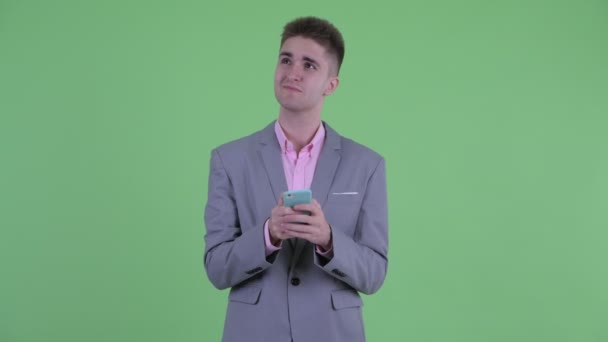 Boldog fiatal üzletember gondolkodás használata közben telefon — Stock videók