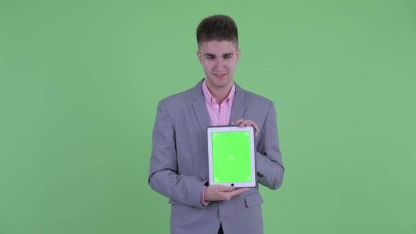 Šťastný mladý podnikatel hovoří při zobrazování digitálního tabletu — Stock video