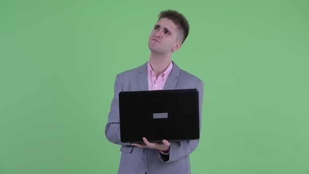 Šťastný mladý obchodník uvažuje při používání přenosného počítače — Stock video