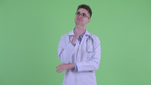 Счастливый молодой человек врач думает и смотрит вверх — стоковое видео