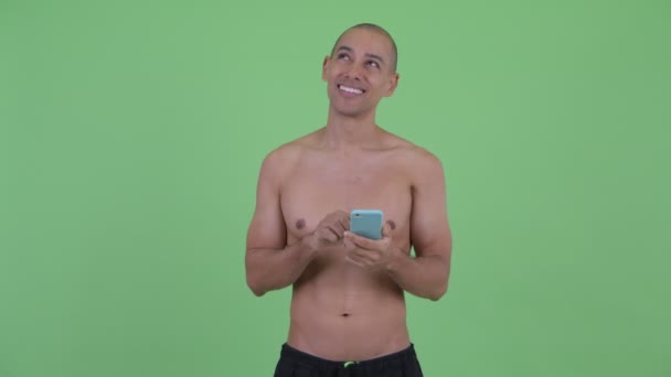 Glücklich glatzköpfige multiethnische hemdlose Mann denken, während mit dem Telefon — Stockvideo