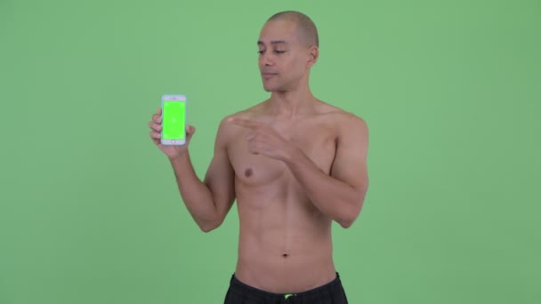 Feliz careca multi étnico sem camisa homem mostrando telefone e dando polegares para cima — Vídeo de Stock