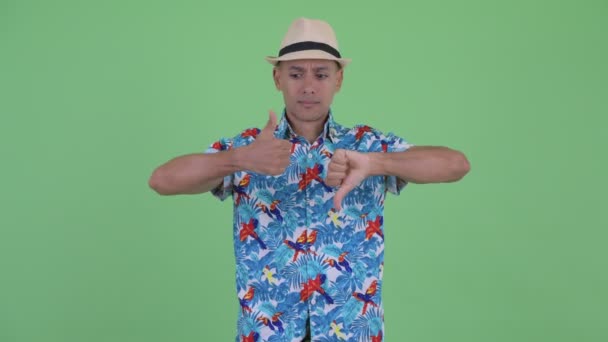 Confused multi ethnic tourist man choosing between thumbs up and thumbs down — Stock Video