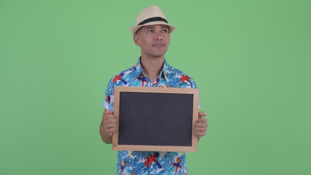 Happy multi ethnic tourist man thinking while holding blackboard — Stock Video