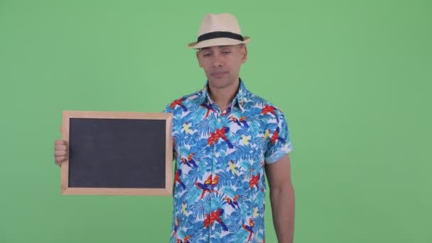 Stressed multi ethnic tourist man holding blackboard and giving thumbs down — Stock Video