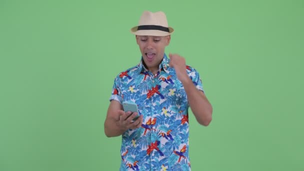 Feliz hombre turístico multiétnico utilizando el teléfono y obtener buenas noticias — Vídeos de Stock