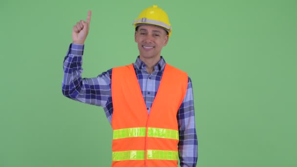 Feliz hombre multiétnico trabajador de la construcción apuntando hacia arriba — Vídeo de stock