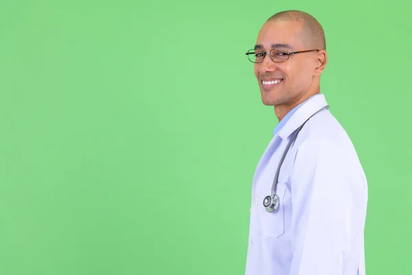 Zbliżenie profil widok z szczęśliwy łysy wielu etnicznych mężczyzna lekarz patrząc na aparat fotograficzny — Zdjęcie stockowe