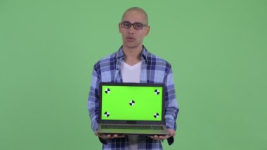 Dizüstü bilgisayar gösterirken mutlu kel hipster adam konuşuyor