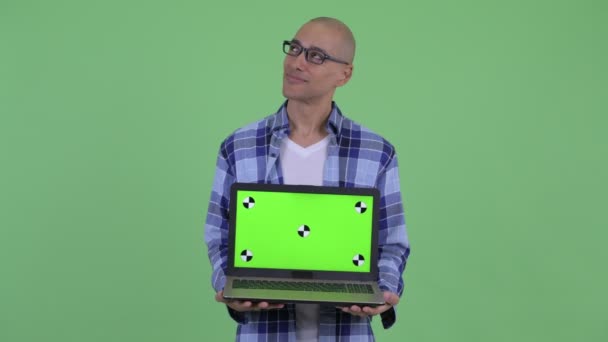 Feliz homem hipster careca pensando ao mostrar laptop — Vídeo de Stock