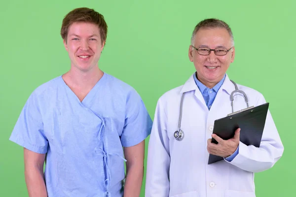 Szczęśliwy dojrzały japoński człowiek lekarz z skandynawski człowiek pacjent uśmiechający się razem — Zdjęcie stockowe