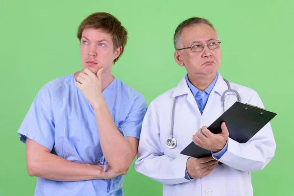 Mogen japansk man läkare med skandinavisk man patient tänkande tillsammans — Stockfoto