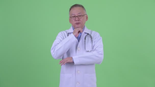 Stressed mature Japanese man doctor thinking and looking down — Stock Video