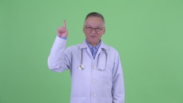 Feliz madura japonesa hombre médico apuntando hacia arriba — Vídeo de stock