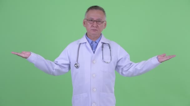 Sério maduro japonês homem médico comparando algo — Vídeo de Stock