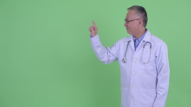 Счастливый взрослый японский врач говорит и трогает что-то — стоковое видео