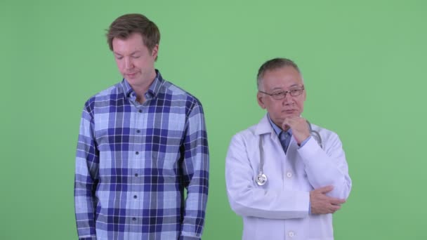 Gestresst reif japanisch mann doktor mit jung mann thinking together — Stockvideo