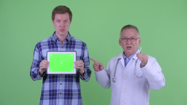 Зрелый японский врач с молодым человеком, объясняющий эффекты курения — стоковое видео