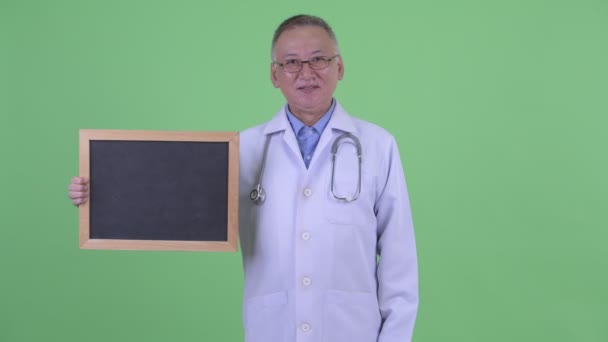 Gelukkig volwassen Japanse man arts Holding Blackboard en het geven van duimen omhoog — Stockvideo