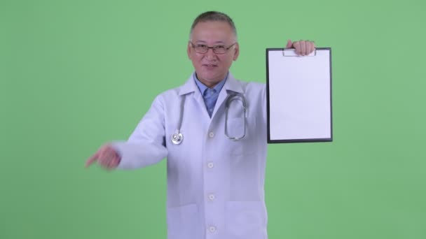 Счастливый взрослый японский врач показывая планшет и показывая большие пальцы вверх — стоковое видео