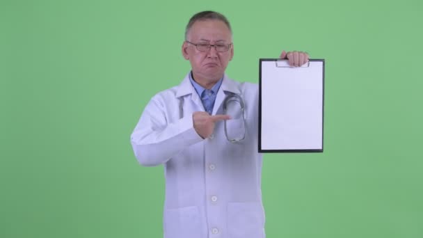 Vystresovaný japonský doktor, který ukazuje schránku a dává palce — Stock video