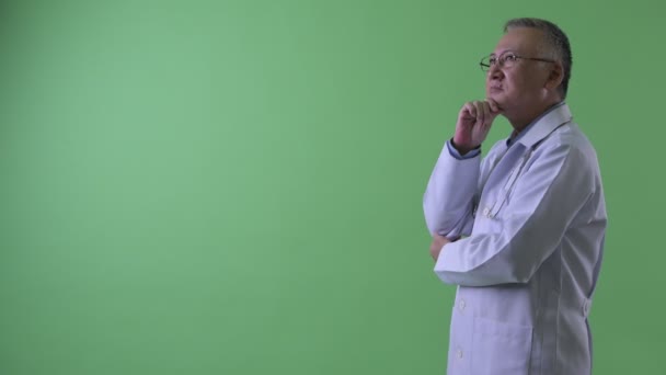 Perfil vista de feliz madura japonesa hombre médico pensando — Vídeo de stock
