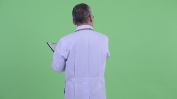 Задний вид счастливого взрослого японского врача, проверяющего с помощью планшета — стоковое видео