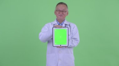 Mutlu olgun Japon adam doktor düşünme dijital tablet gösterirken