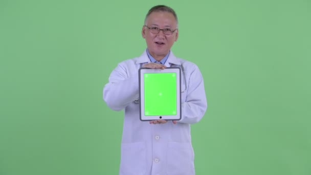 Feliz madura japonesa hombre médico hablando mientras muestra tableta digital — Vídeo de stock