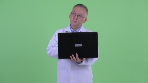 Feliz maduro japonês homem médico pensando ao usar laptop — Vídeo de Stock