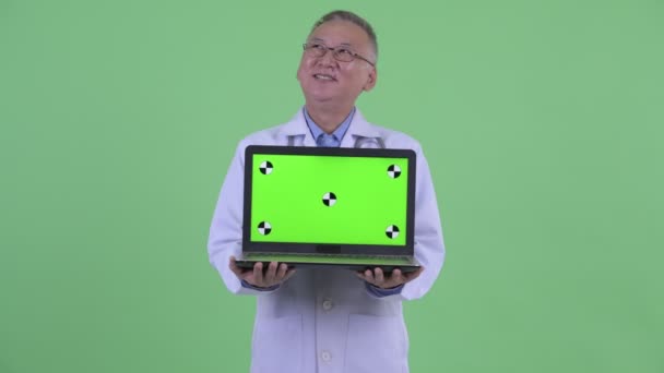 Felice maturo giapponese uomo medico pensando mentre mostra laptop — Video Stock