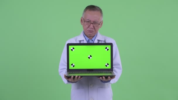 Estresado maduro japonés hombre médico mostrando laptop — Vídeos de Stock