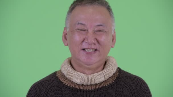 Gezicht van gelukkige volwassen Japanse man glimlachend en lachen klaar voor de winter — Stockvideo