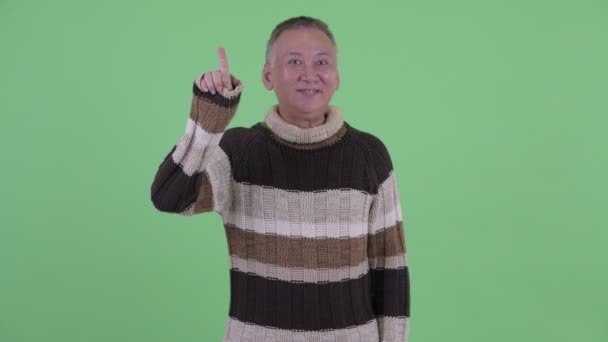 Happy mature Japanese man pointing up ready for winter — Stock Video