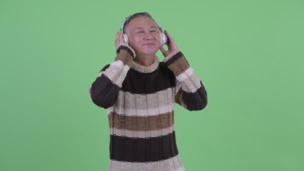 Happy mature Japanese man listening to music — Stock Video