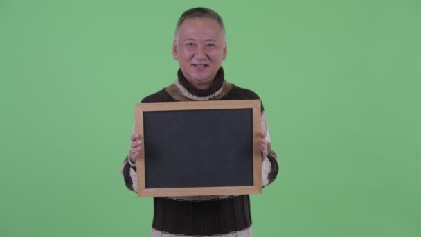 Šťastný zralý japonský muž, který si povídá o držení tabule — Stock video