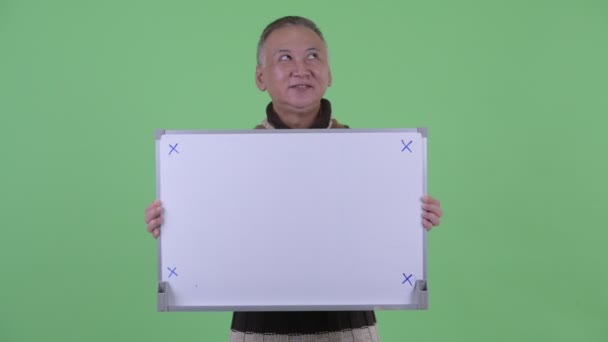 Щаслива зріла Японська людина думає при проведенні білої дошки — стокове відео