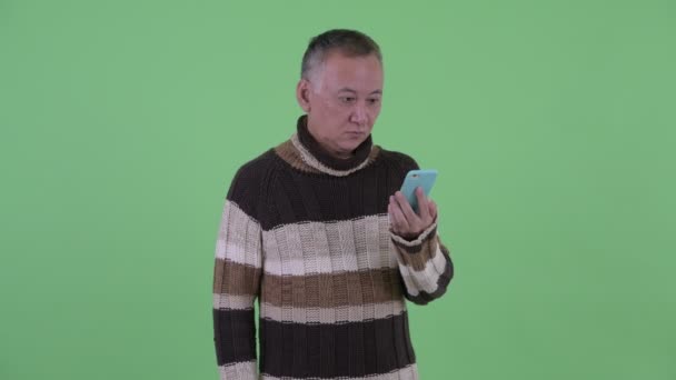 Happy mature Japanese man using phone and looking surprised — Stock Video