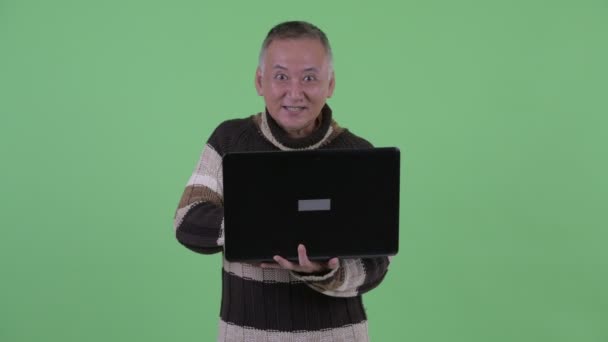 Felice uomo giapponese maturo pensando durante l'utilizzo di laptop e parlando — Video Stock